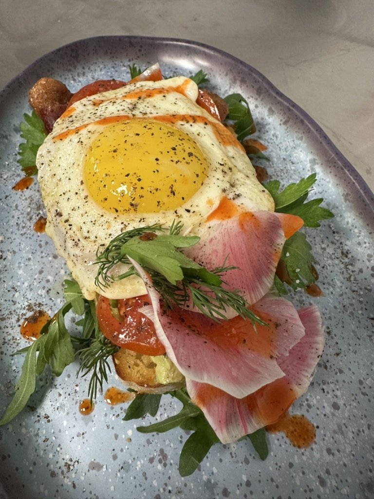 Open-face breakfast toast with fried egg, watermelon radish and arugula