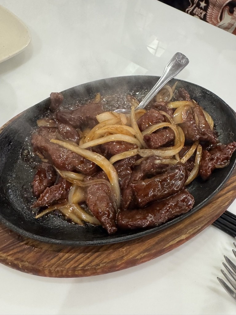 Sizzling Mongolian beef with onions on a cast iron skillet